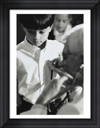 Framed Male doctor listening to a boy&#39;s heartbeat Print
