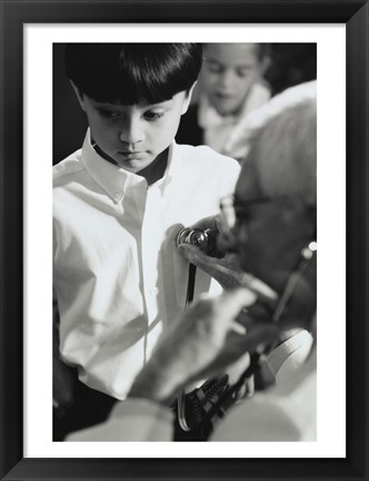 Framed Male doctor listening to a boy&#39;s heartbeat Print