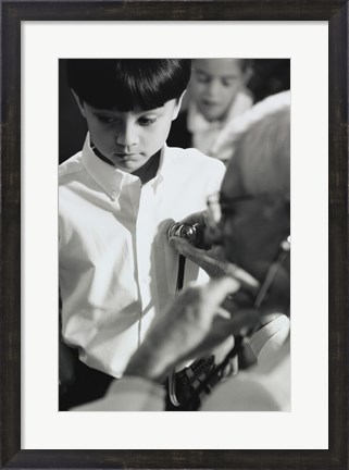 Framed Male doctor listening to a boy&#39;s heartbeat Print