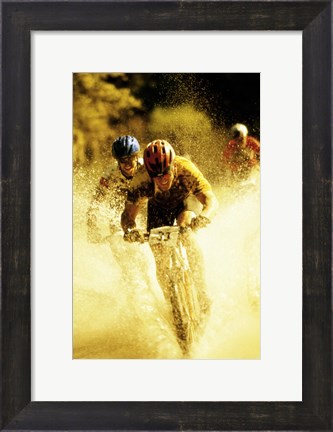 Framed Young men riding bicycles through water Print