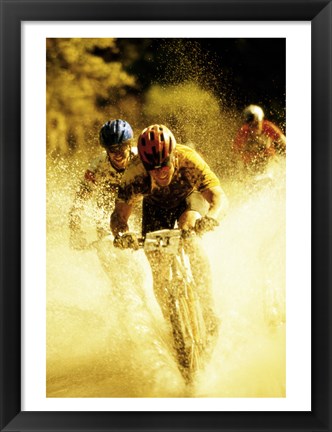 Framed Young men riding bicycles through water Print