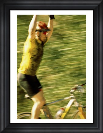 Framed Young man sitting on a bicycle with his arms raised Print