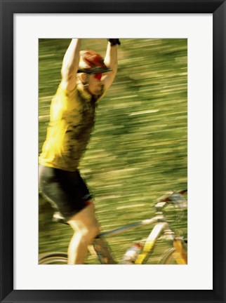 Framed Young man sitting on a bicycle with his arms raised Print