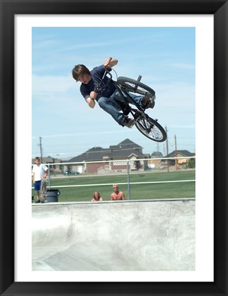 Framed Low angle view of a teenage boy performing a stunt on a bicycle over ramp Print