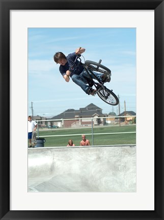 Framed Low angle view of a teenage boy performing a stunt on a bicycle over ramp Print