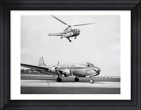Framed Low angle view of a helicopter in flight and an airplane at an airport, Sikorsky Helicopter, Douglas DC-4 Print