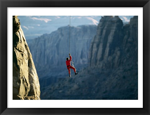 Framed Rear view of a man rappelling down a rock Print