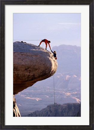 Framed Side profile of a young man pulling a young woman onto a rock Print