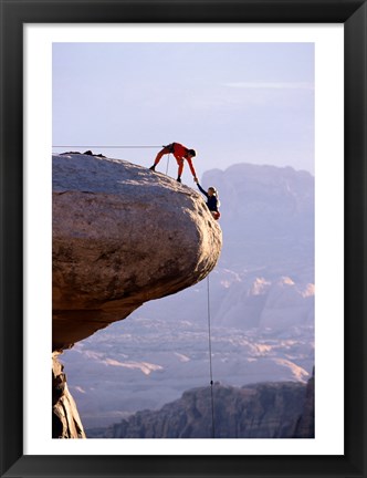 Framed Side profile of a young man pulling a young woman onto a rock Print