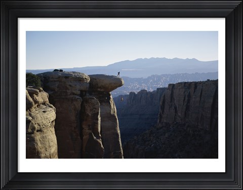 Framed Side profile of a young man pulling a young woman onto a rock Print