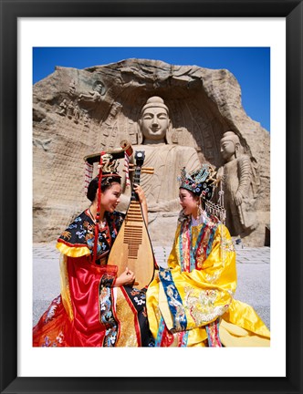 Framed Two girls in traditional costumes in front of the Buddha Statue, China Print