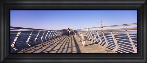 Framed Couple walking on a pier, Bay Bridge, San Francisco, California, USA Print