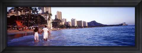Framed Rear view of a couple wading on the beach, Waikiki Beach, Honolulu, Oahu, Hawaii, USA Print