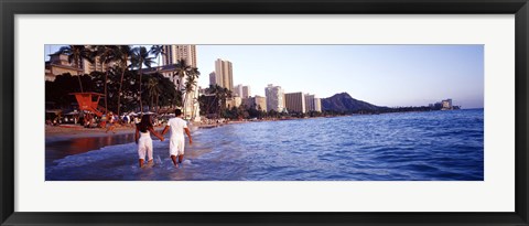 Framed Rear view of a couple wading on the beach, Waikiki Beach, Honolulu, Oahu, Hawaii, USA Print