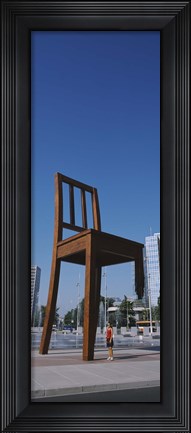 Framed Woman standing under a sculpture of large broken chair, Geneva, Switzerland Print
