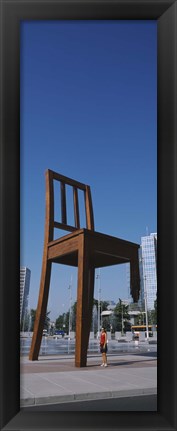 Framed Woman standing under a sculpture of large broken chair, Geneva, Switzerland Print