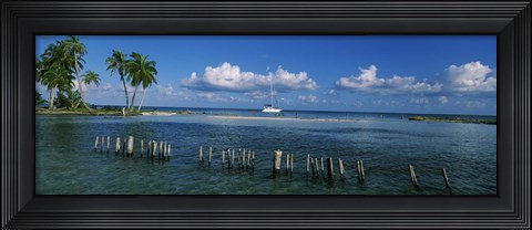 Framed Wooden posts in the sea with a boat in background, Laughing Bird Caye, Victoria Channel, Belize Print