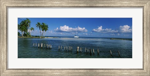 Framed Wooden posts in the sea with a boat in background, Laughing Bird Caye, Victoria Channel, Belize Print