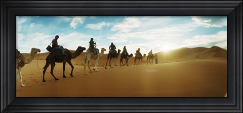 Framed Tourists riding camels through the Sahara Desert landscape led by a Berber man, Morocco Print