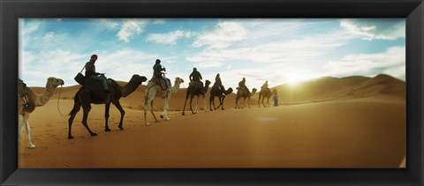 Framed Tourists riding camels through the Sahara Desert landscape led by a Berber man, Morocco Print