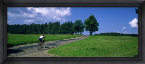 Framed Rear view of a person riding a bicycle on the road, Black Forest, Germany Print