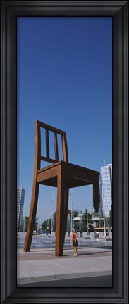 Framed Woman standing under a sculpture of large broken chair, Geneva, Switzerland Print