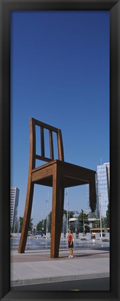 Framed Woman standing under a sculpture of large broken chair, Geneva, Switzerland Print