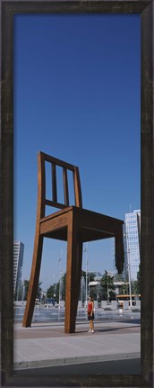 Framed Woman standing under a sculpture of large broken chair, Geneva, Switzerland Print