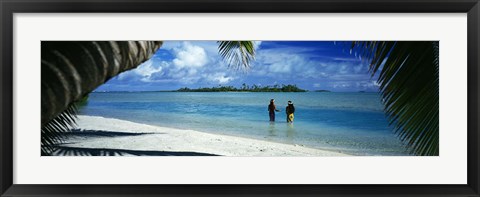 Framed Rear view of two native teenage girls in lagoon, framed by palm tree, Aitutaki, Cook Islands. Print