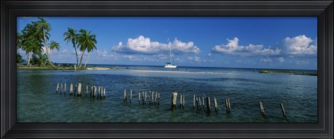 Framed Wooden posts in the sea with a boat in background, Laughing Bird Caye, Victoria Channel, Belize Print