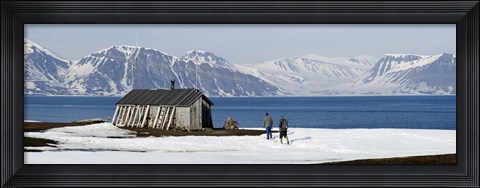 Framed Two hikers standing on the beach near a hunting cabin, Bellsund, Spitsbergen, Svalbard Islands, Norway Print