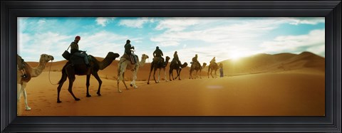 Framed Tourists riding camels through the Sahara Desert landscape led by a Berber man, Morocco Print