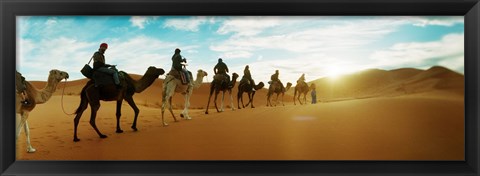 Framed Tourists riding camels through the Sahara Desert landscape led by a Berber man, Morocco Print