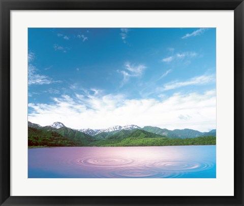 Framed Pink light cast down on two rings in lavender water with deep blue sky and clouds over green mountains in distance Print