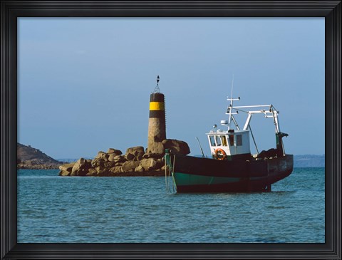Framed Fishing trawler in front of a lighthouse at Port Saint-Sauveur, Ile Grande, Cotes-d&#39;Armor, Brittany, France Print