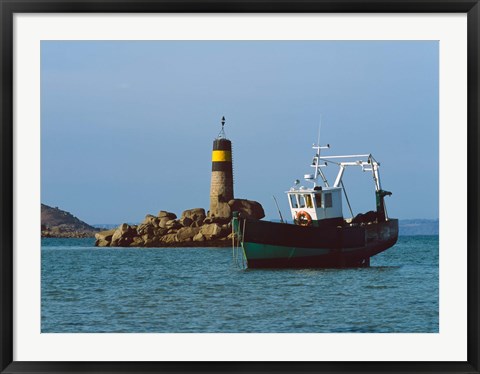 Framed Fishing trawler in front of a lighthouse at Port Saint-Sauveur, Ile Grande, Cotes-d&#39;Armor, Brittany, France Print