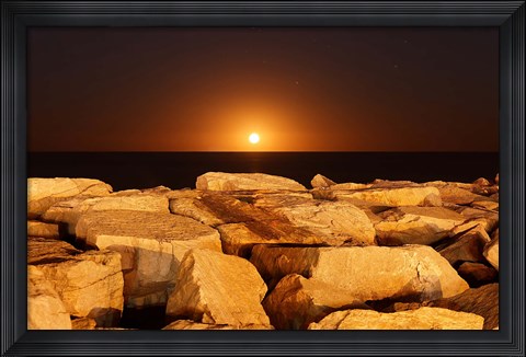 Framed moon rising behind rocks lit by a nearby fire in Miramar, Argentina Print