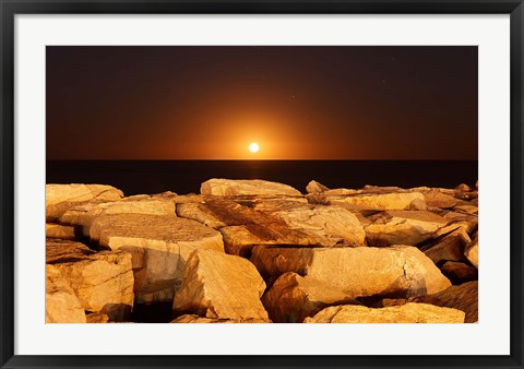 Framed moon rising behind rocks lit by a nearby fire in Miramar, Argentina Print