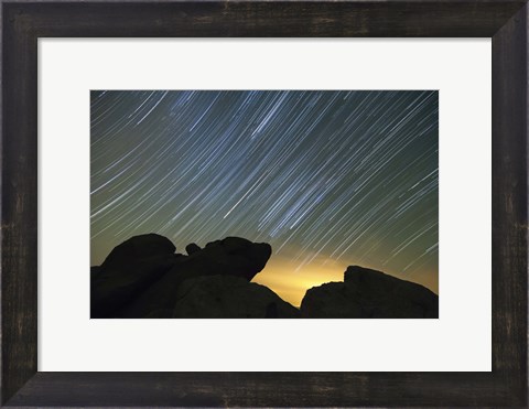 Framed Light pollution illuminates the sky and star tails above large boulders Print