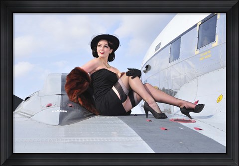 Framed Glamorous woman in 1940&#39;s style attire sitting on a vintage aircraft Print