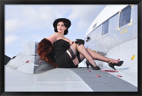 Framed Glamorous woman in 1940&#39;s style attire sitting on a vintage aircraft Print