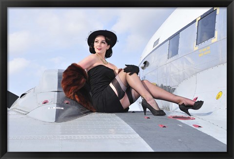 Framed Glamorous woman in 1940&#39;s style attire sitting on a vintage aircraft Print