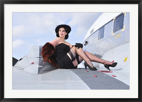 Framed Glamorous woman in 1940&#39;s style attire sitting on a vintage aircraft Print