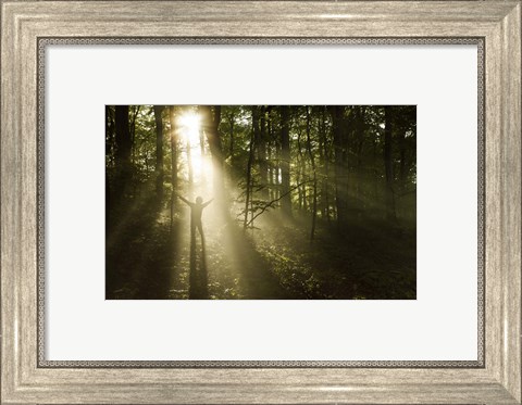 Framed Silhouette of a man standing in the sunrays of a dark, misty forest, Denmark Print